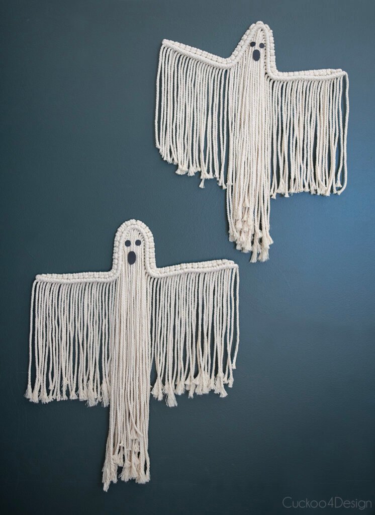 Dos fantasmas de Macrame colgando en una pared verde oscuro